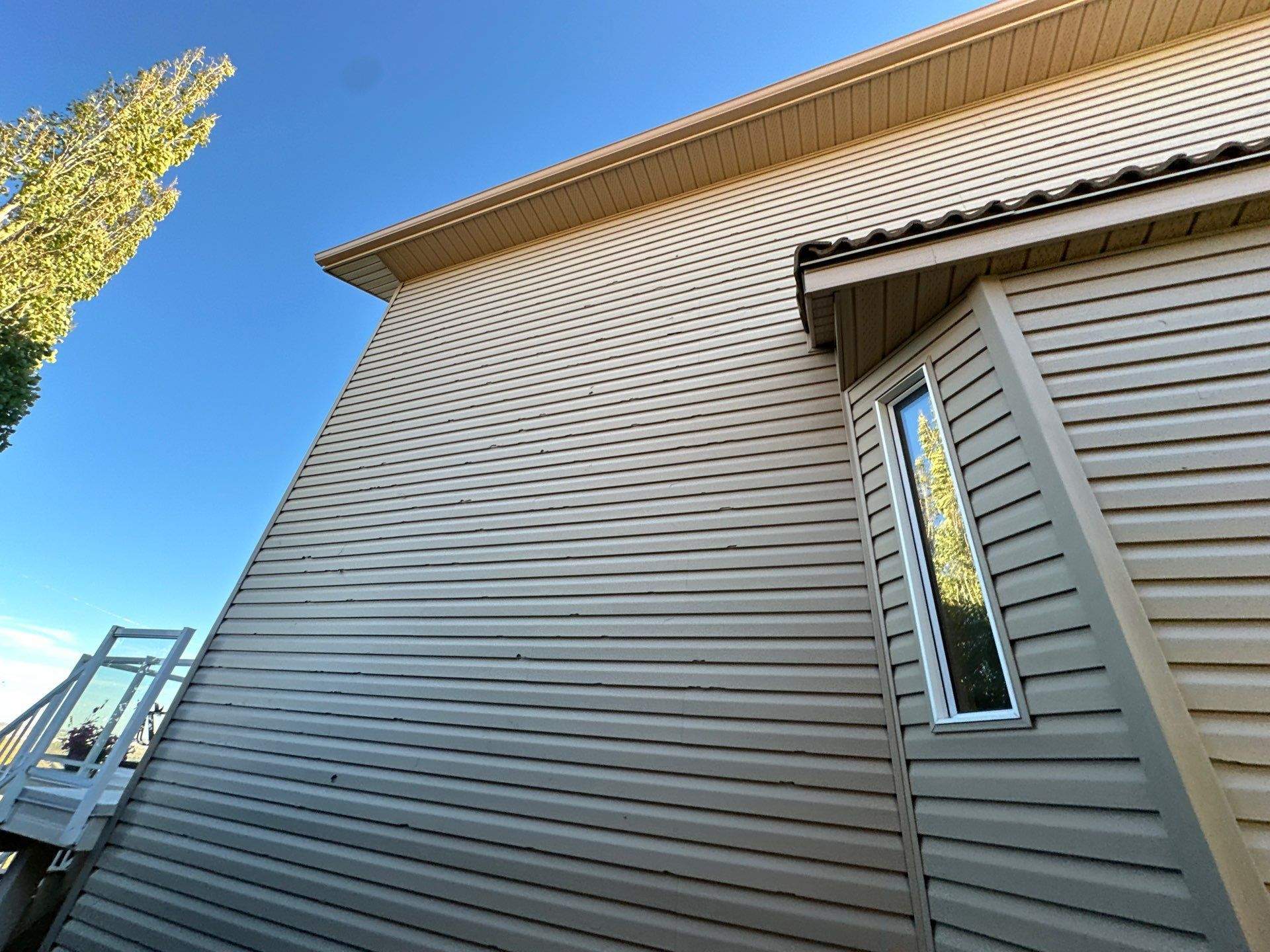 Warped and cracked vinyl siding with visible gaps on a home’s exterior.