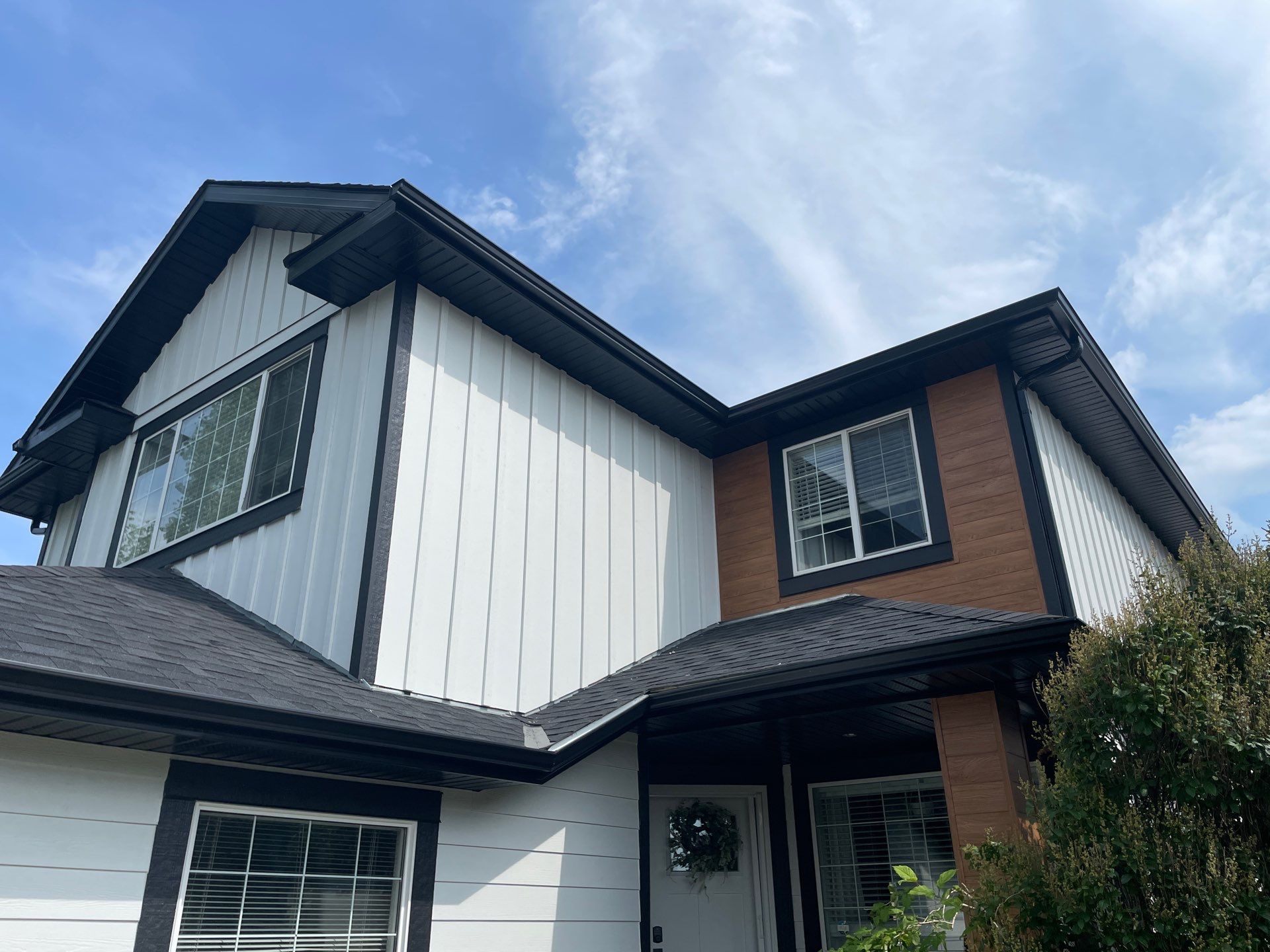 Modern home with white James Hardie siding, wood accents and black trim.