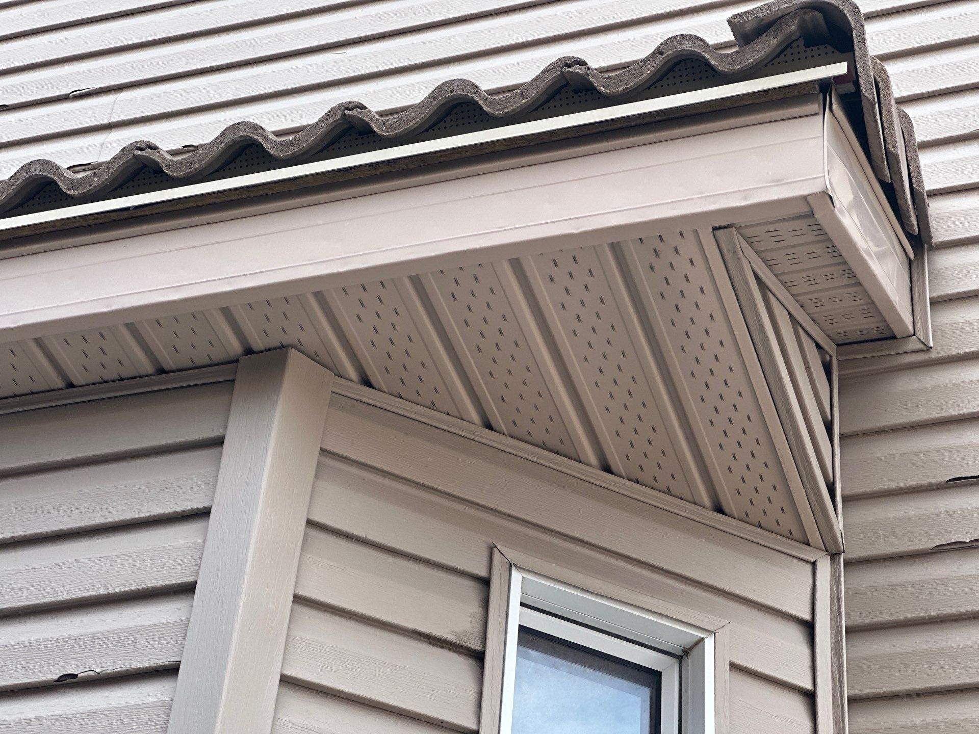 Close-up of vented soffit and fascia beneath a tiled roof overhang.
