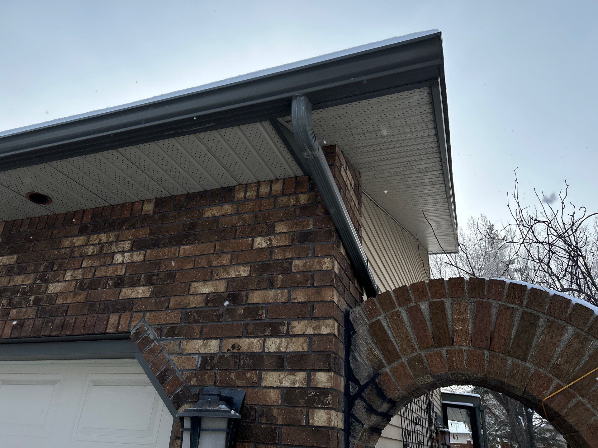 Bent downspout beneath the vented soffit of a brick home.