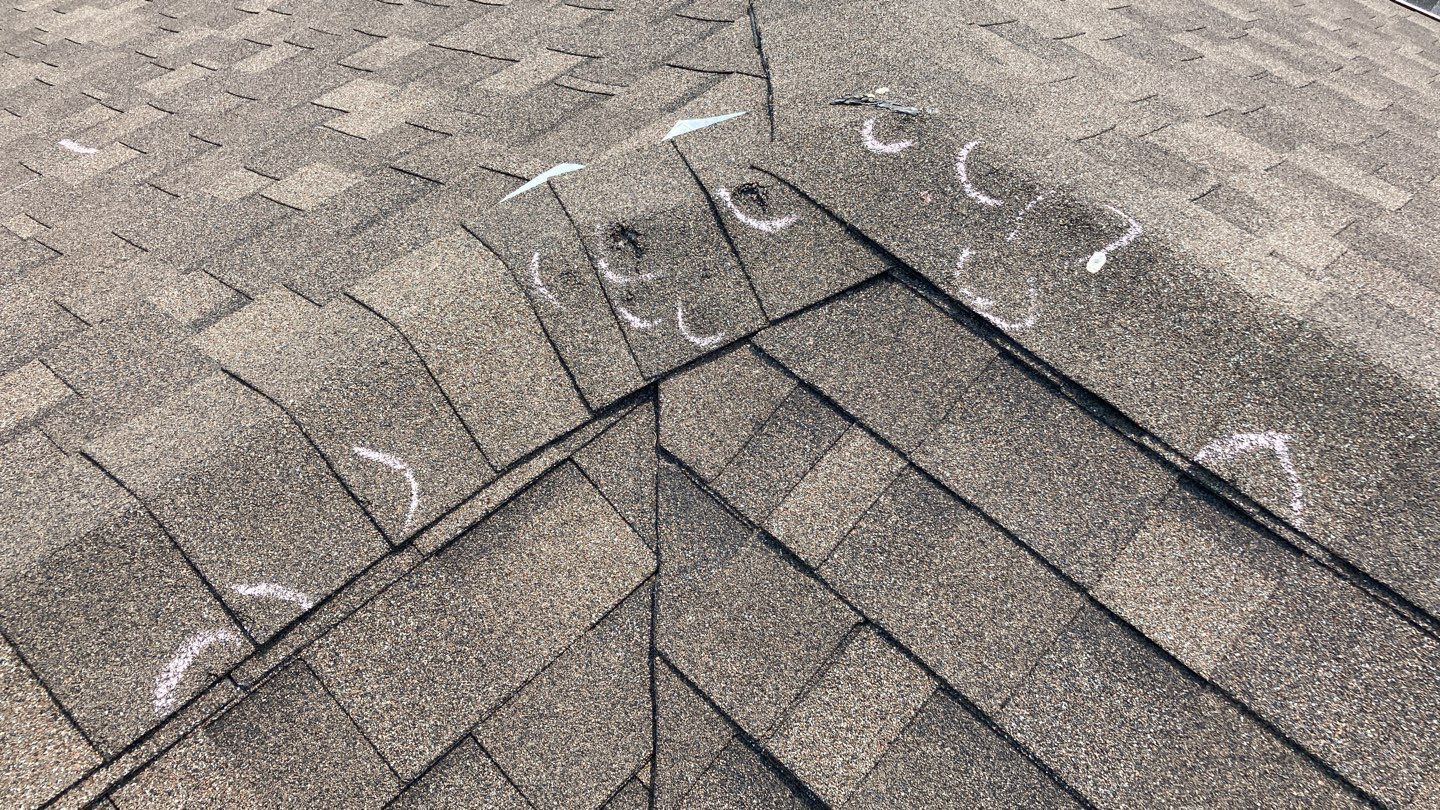 Roof shingles marked with chalk to show hail damage.