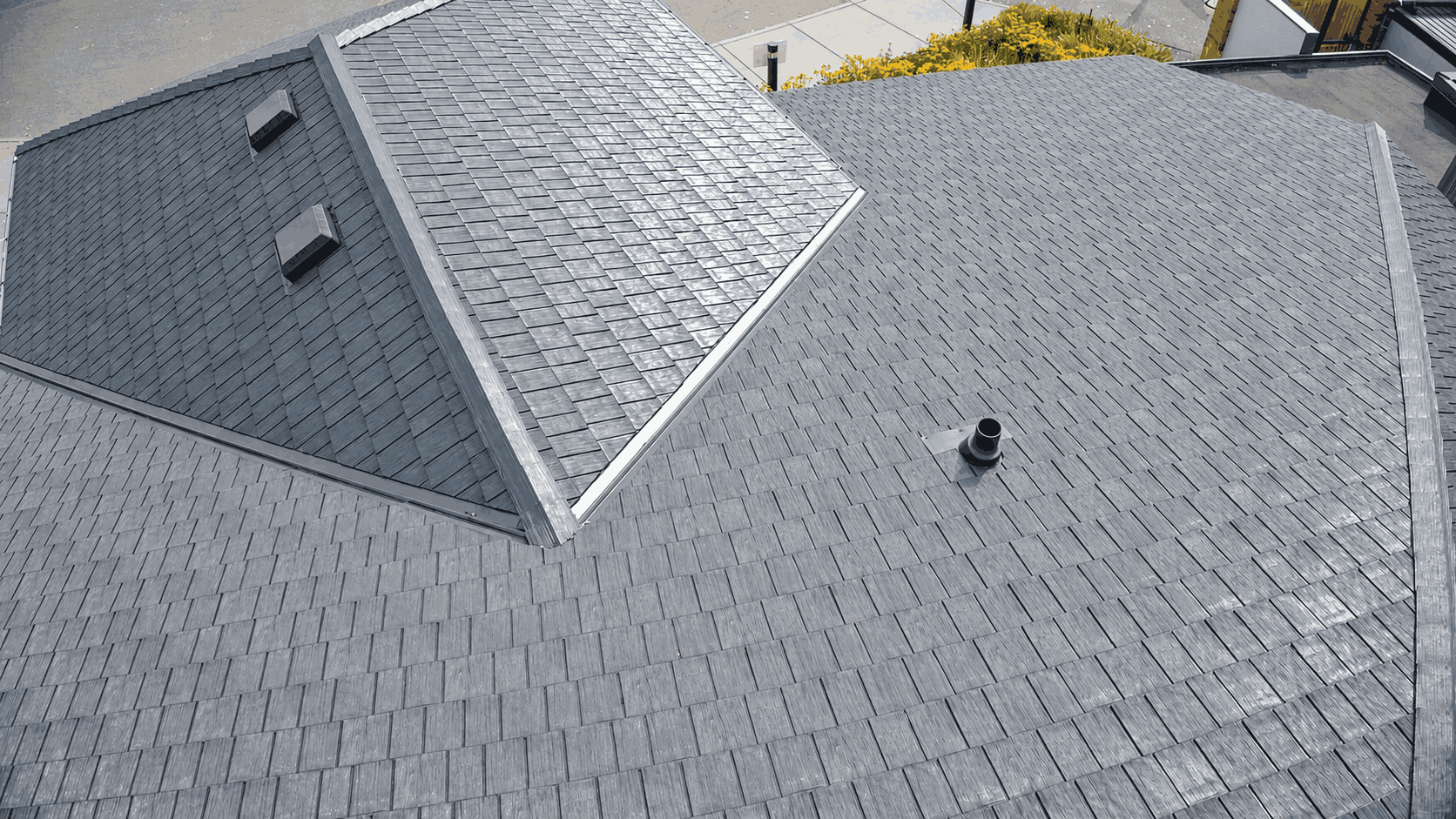 Overhead view of a clean grey rubber shingle roof with skylights and vents.