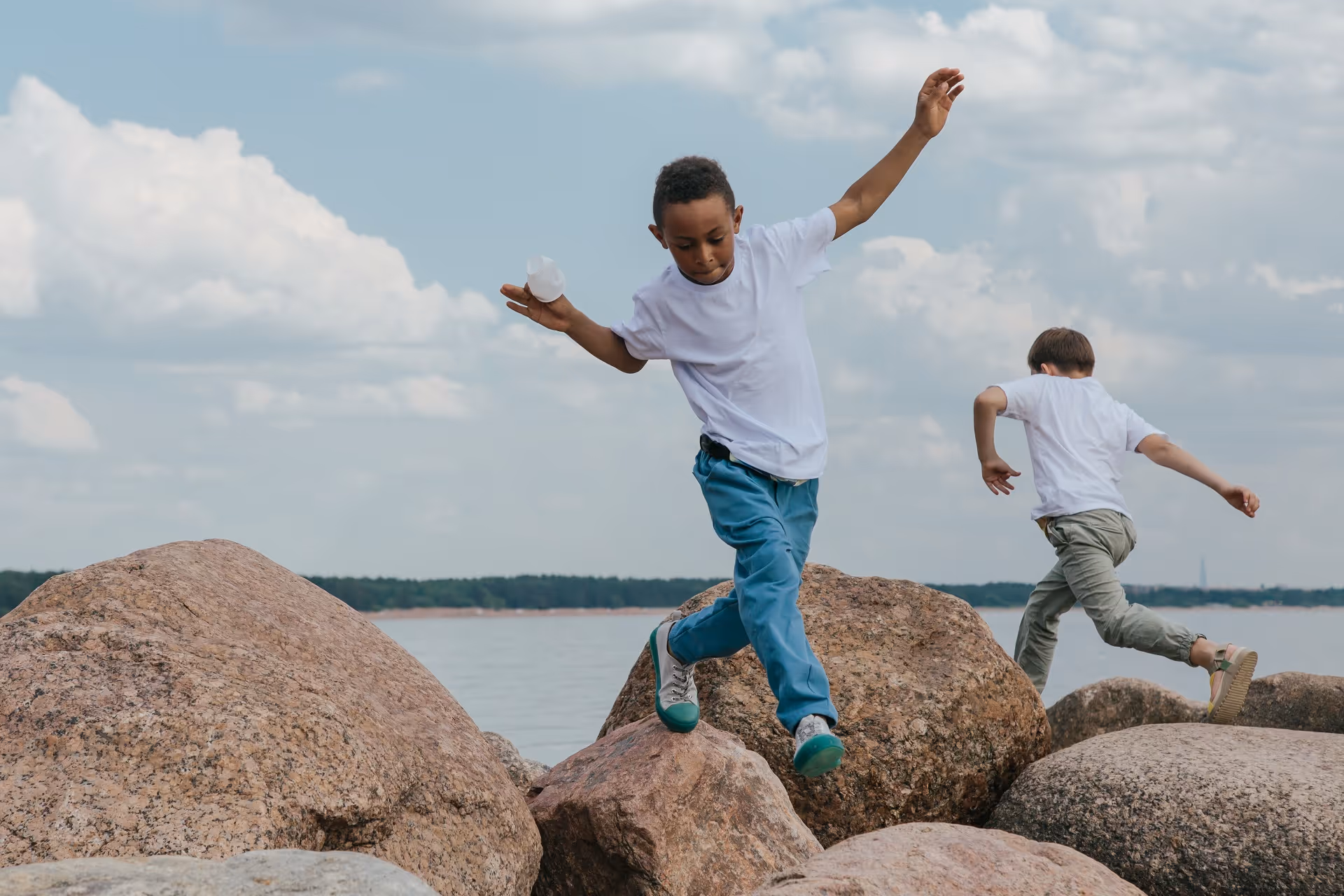 Jungen springen auf riesige Steinen am Strand