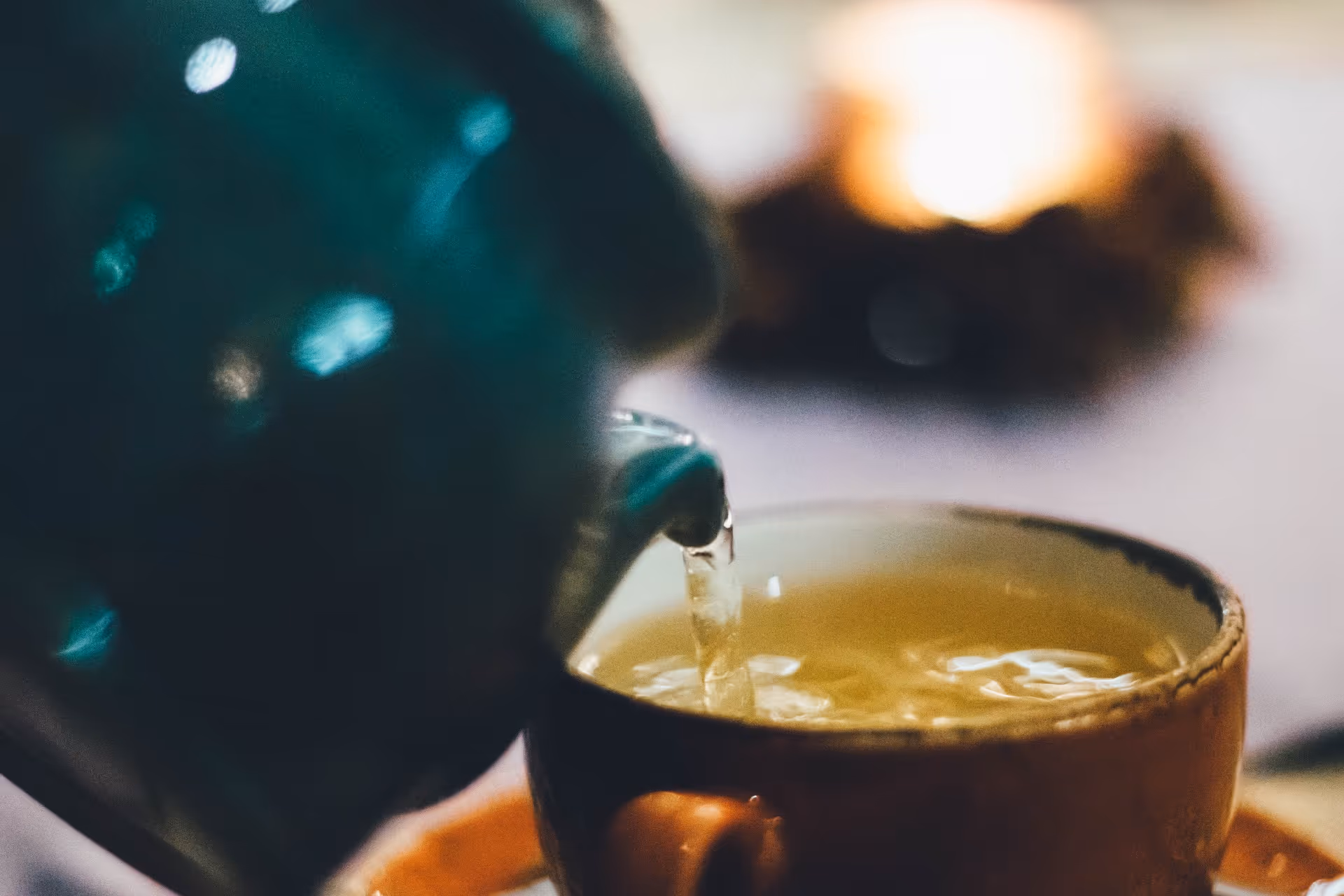 Kräutertee wird aus einer Teekanne in eine Tasse gegossen