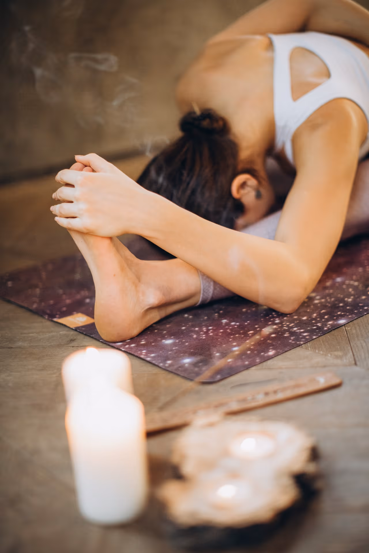 woman performing a Yoga asana with candle and incense burning