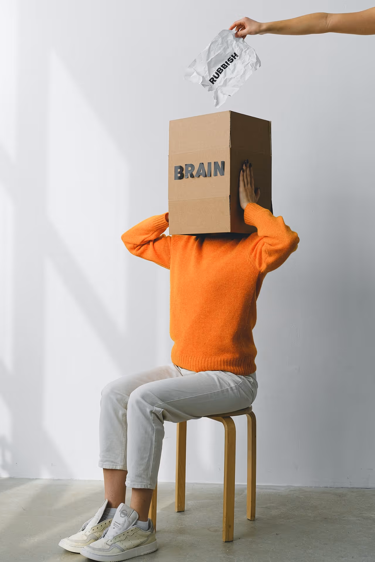 Person with a "brainbox" head being fed with rubbish