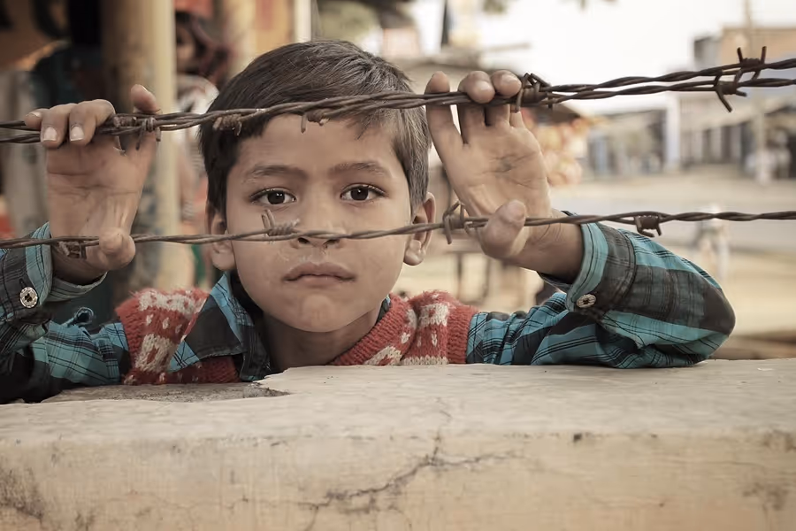 Young Indian boy peers through barbed wire