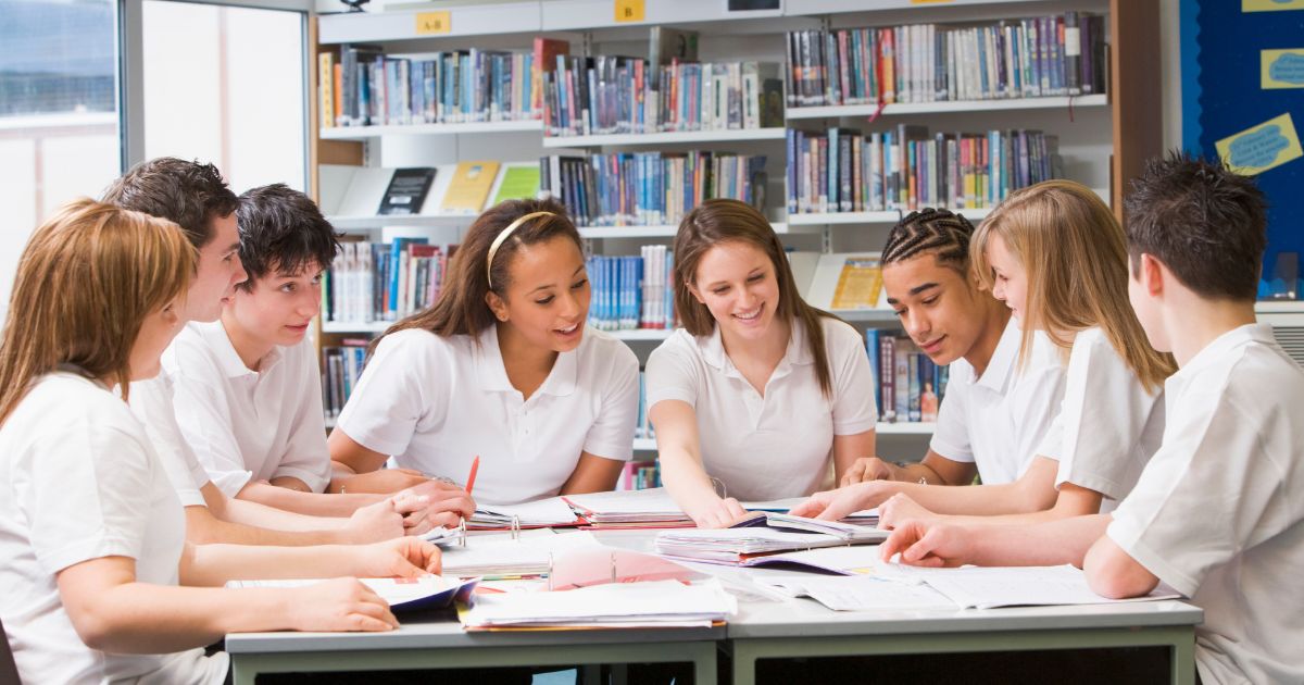 Group of secondary school students in school library working on a project