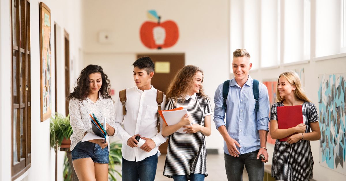 Happy students walking through a school corridor