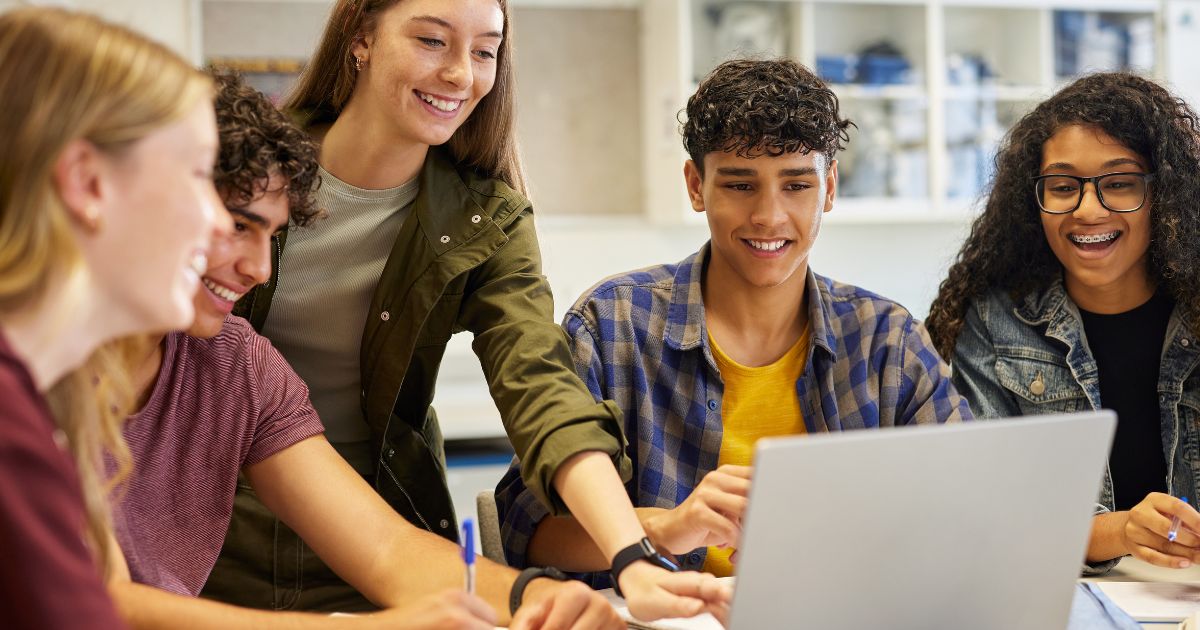 group of post 16 students looking at a laptop smiling