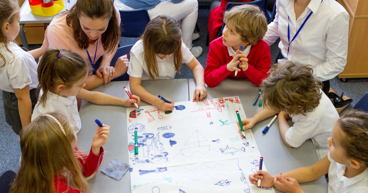 primary school children drawing a wellbeing picture with teachers