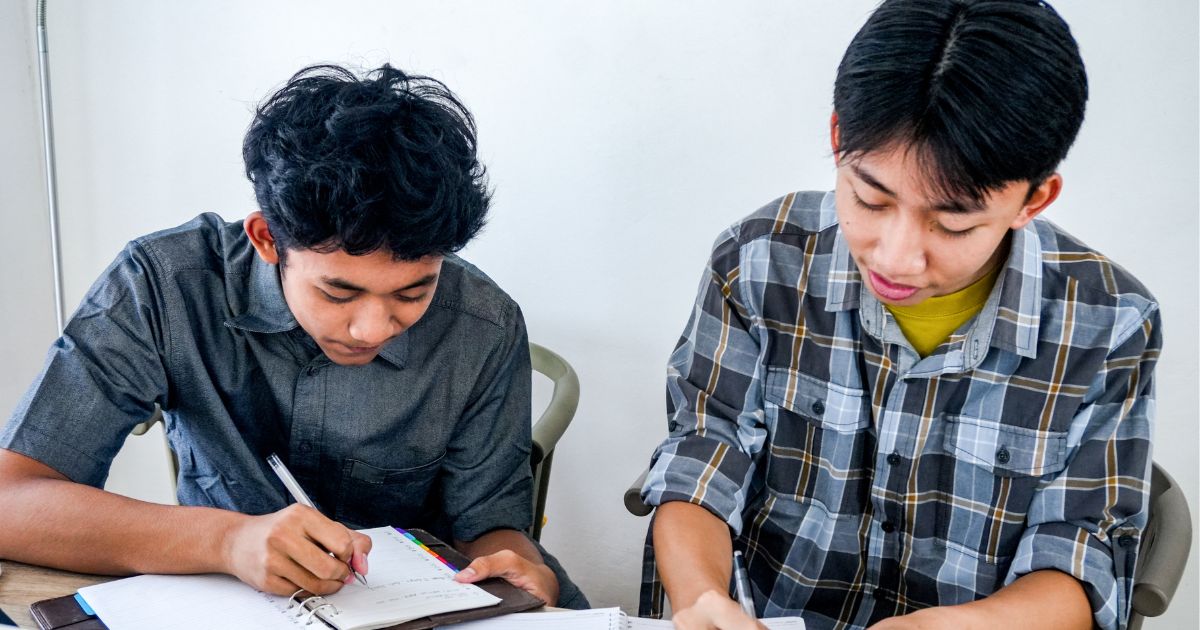 two teenage school boys who are peer mentors writing notes
