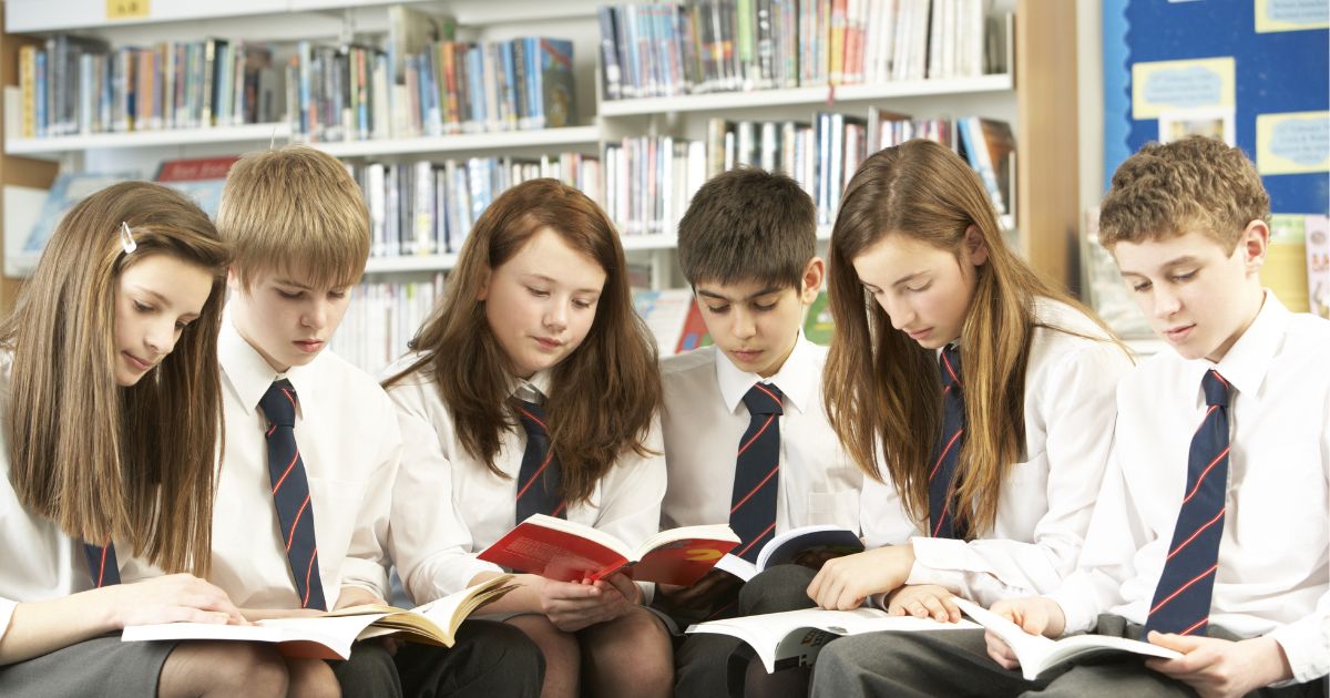 Group of secondary school students reading in the library