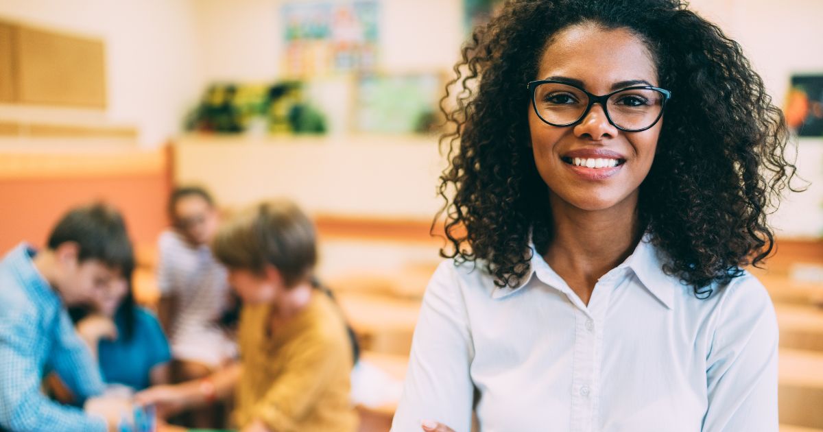 Teacher in inclusion base with students doing group work in background