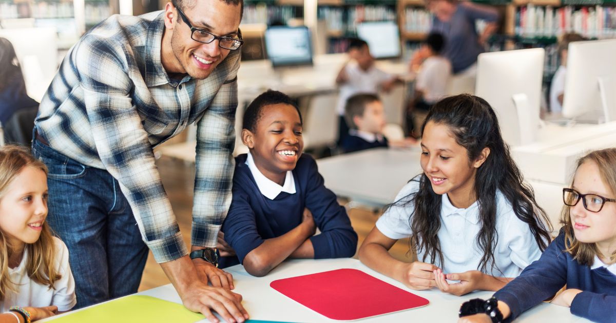 group of primary school children working with black male teacher