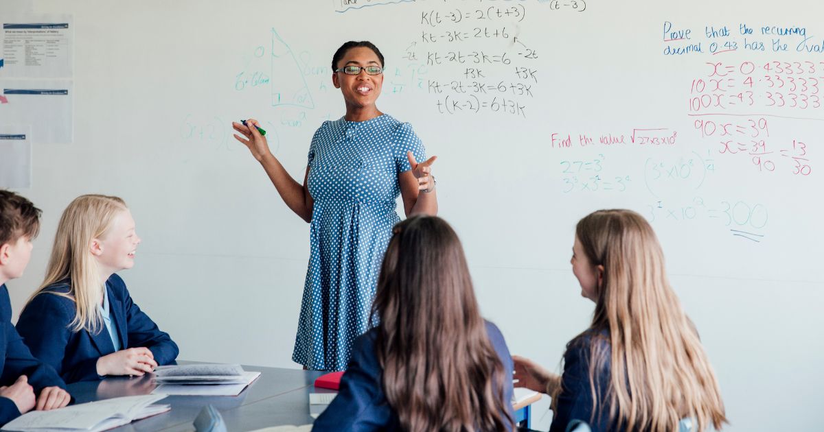 Teacher teaching small group of students maths lesson as targeted support intervention