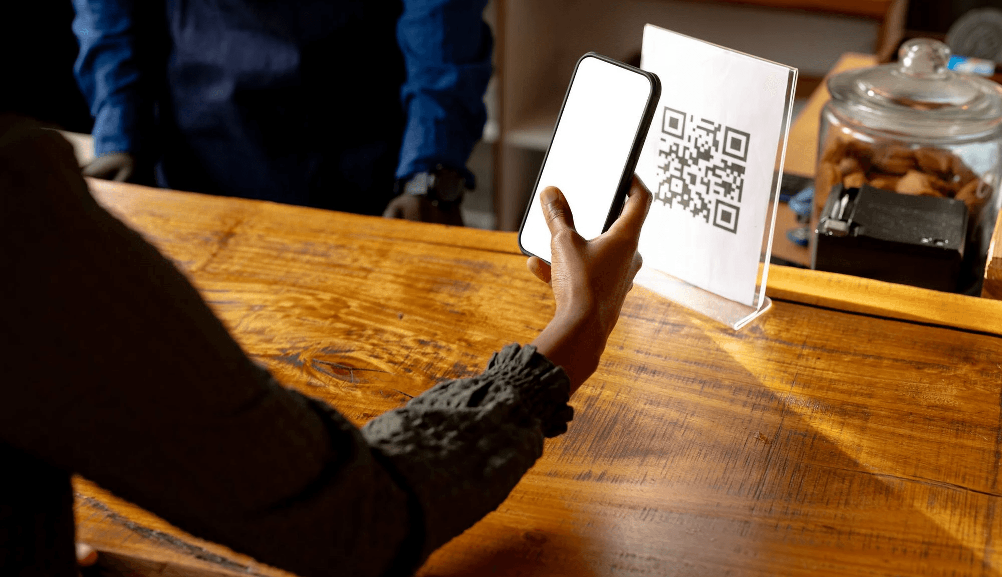 Person scanning QR code at counter - How Much Does a QR Code Cost