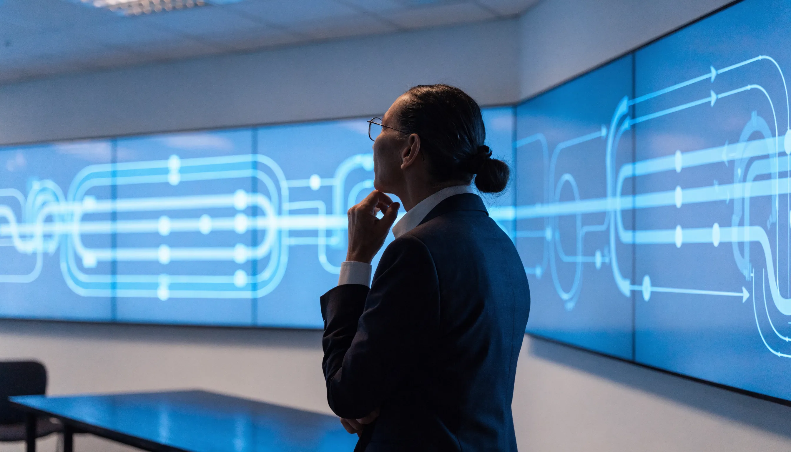 An executive reviews process diagrams on large screens and weighs the decision to invest in an ERP system