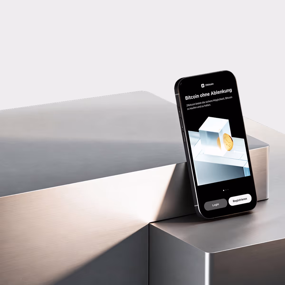 Smartphone steht lässig auf einer silbernen metallischen Oberfläche und zeigt eine Bitcoin-App mit den Optionen Login und Registrieren.