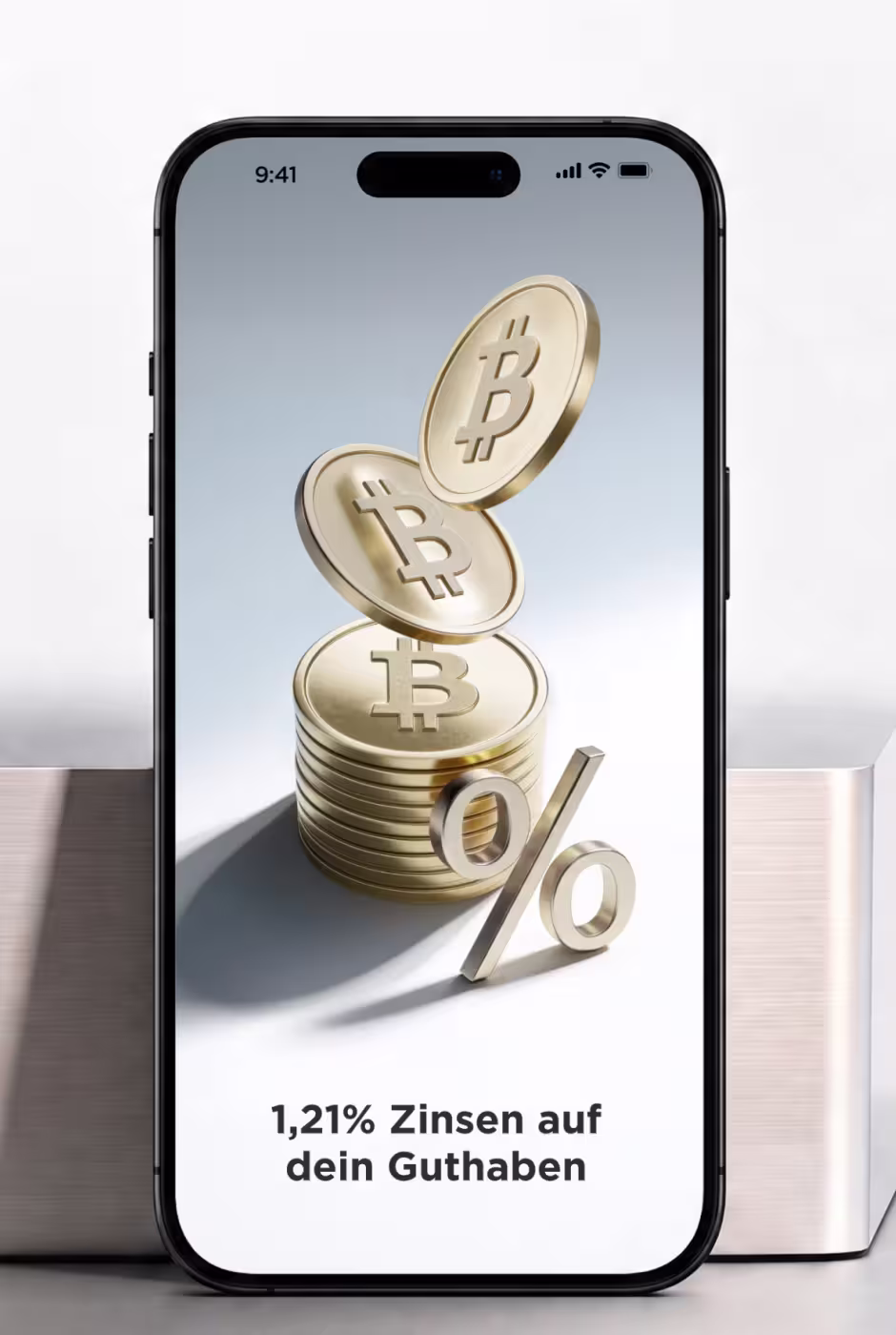 Smartphone zeigt eine Grafik von gestapelten Bitcoin-Münzen und einem großen Prozentzeichen, mit der Textnachricht '1,21% Zinsen auf dein Guthaben'.