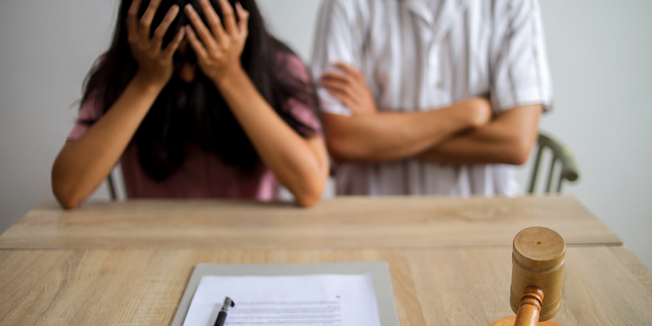 Frau und Mann sitzen vor Scheidungsdokumenten und Richterhammer