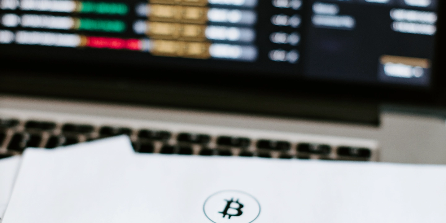 Papier mit Bitcoin und Trading-Screen