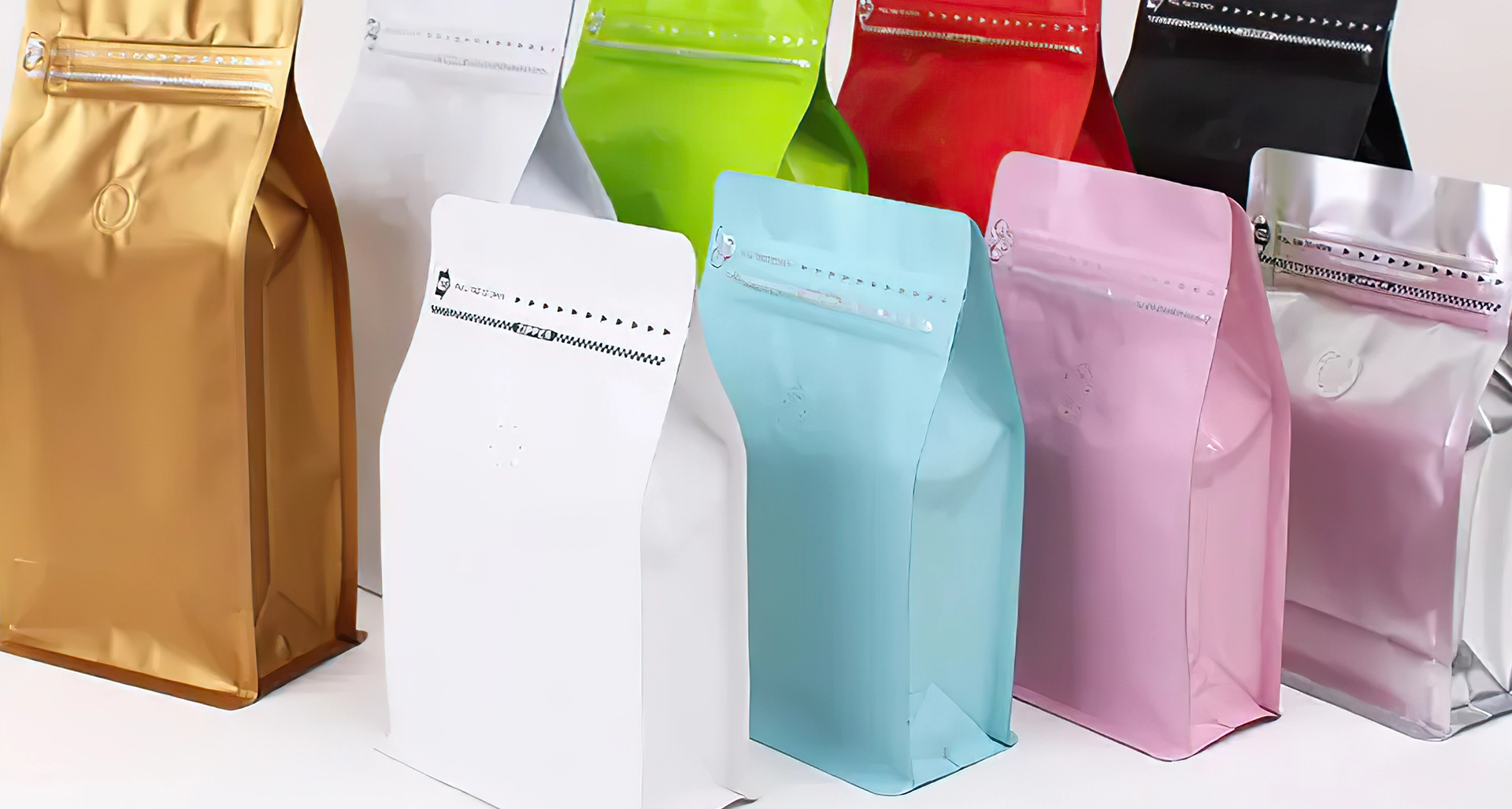 Row of stand-up resealable plastic pouches in various colors including gold, white, green, blue, pink, red, black, and silver on a white background.