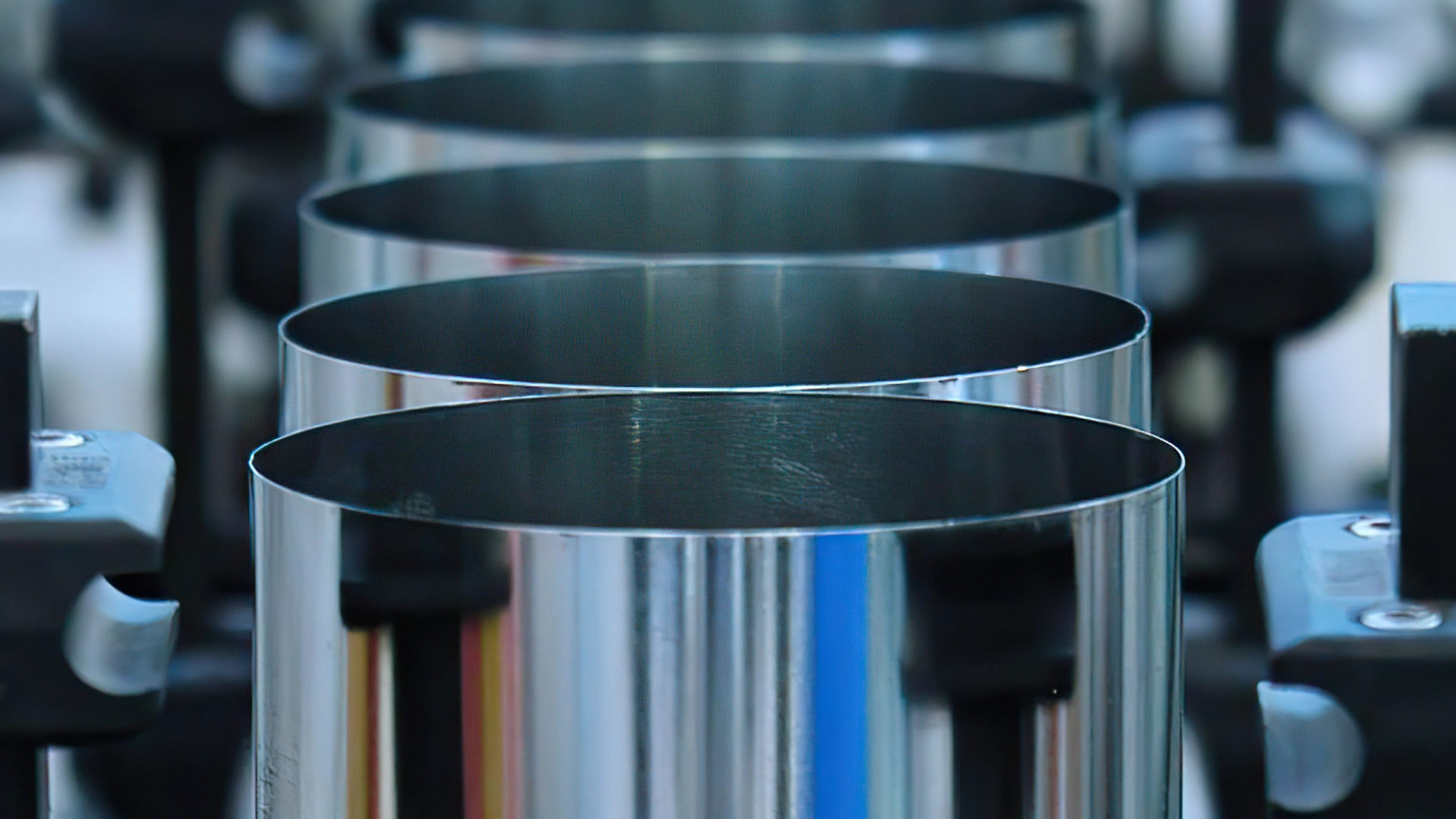 Close-up view of several empty cylindrical metal cans lined up in a row, part of a manufacturing process.