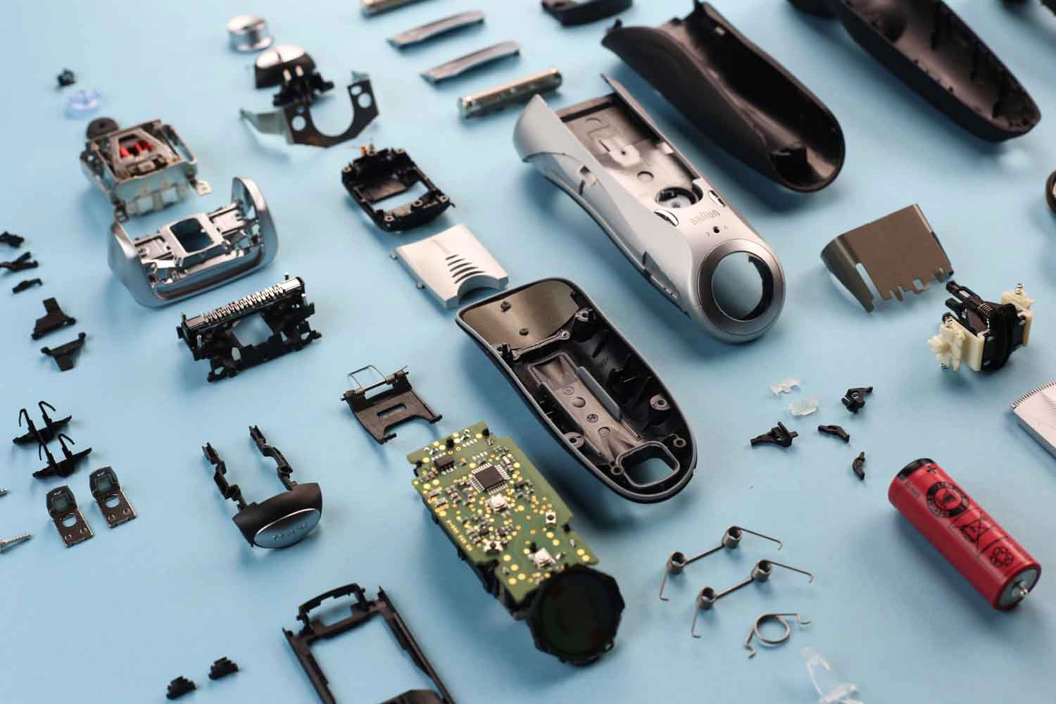 Disassembled electric shaver components spread out on a light blue surface.