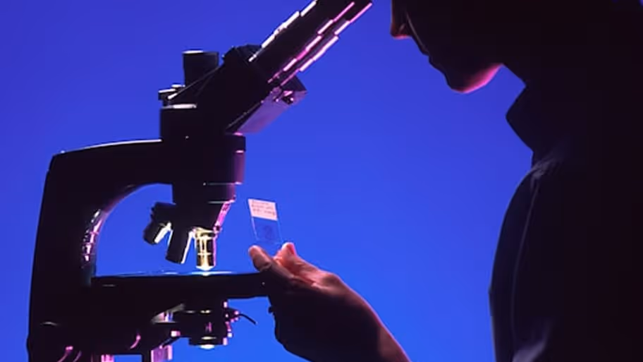 A man looking through a microscope at something.