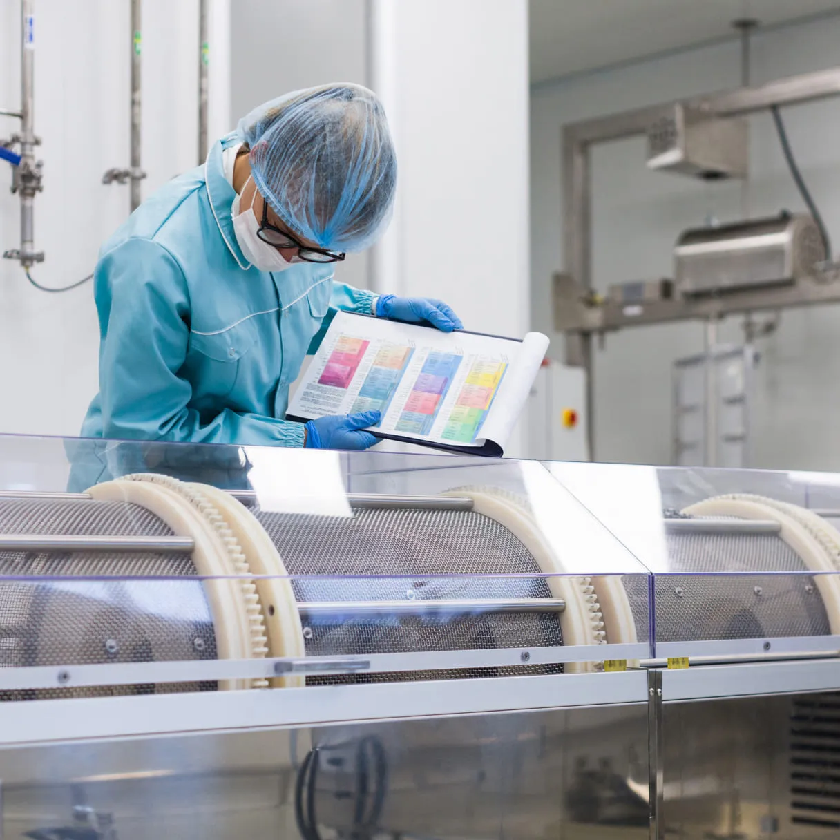 A man in a blue shirt and blue gloves is looking at a book.
