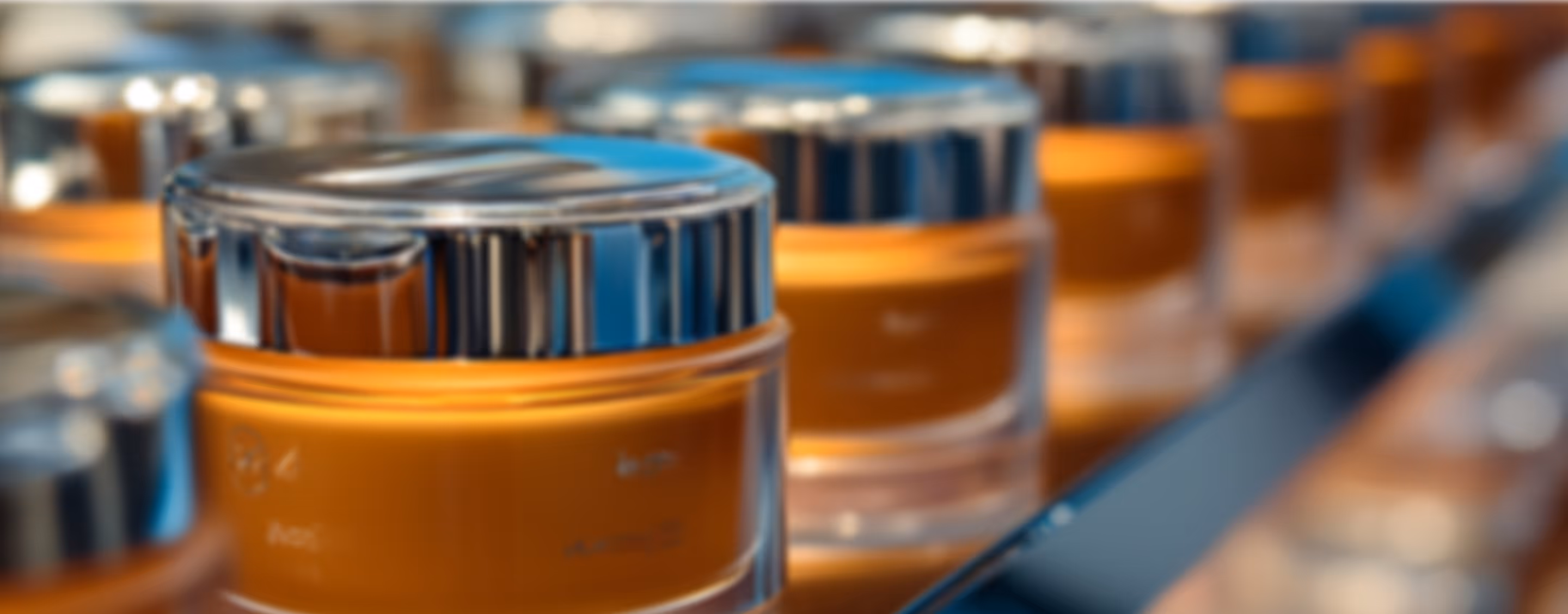 Close-up of small cosmetic jars with silver lids arranged in a row on a reflective surface.
