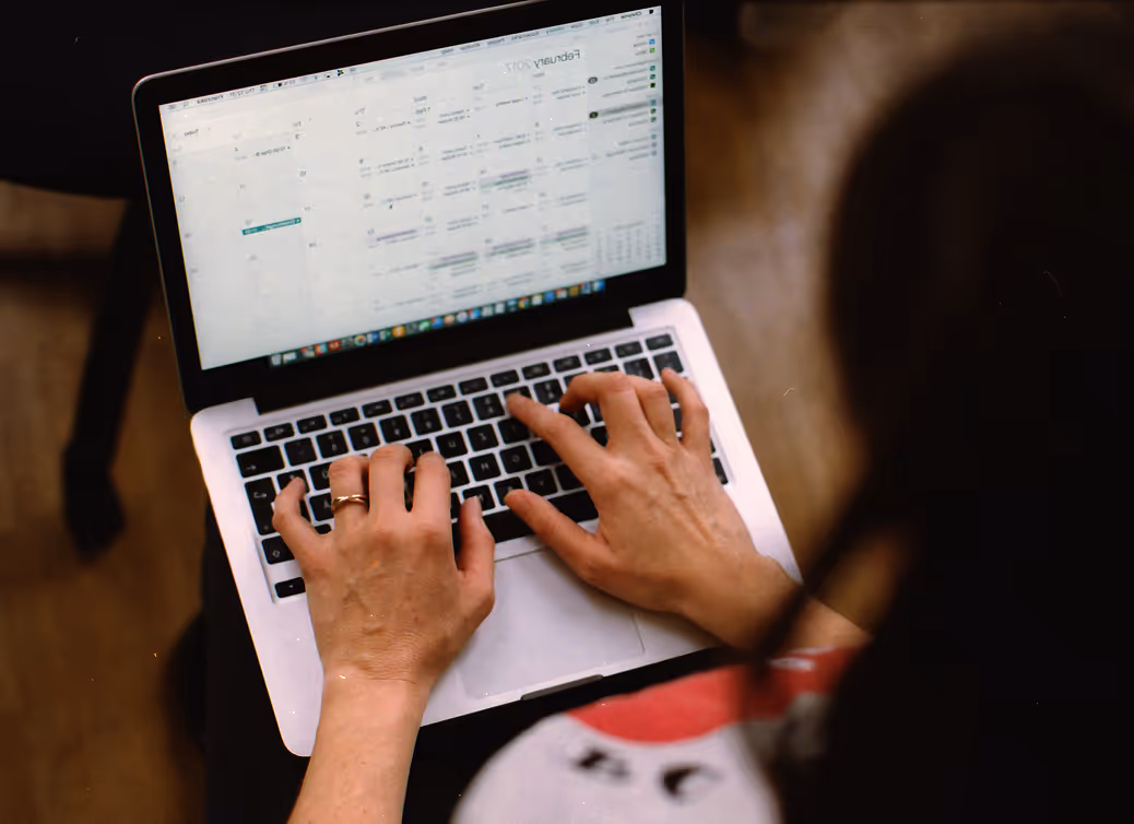 Person typing on a laptop displaying a calendar app with February 2017 visible on the screen.