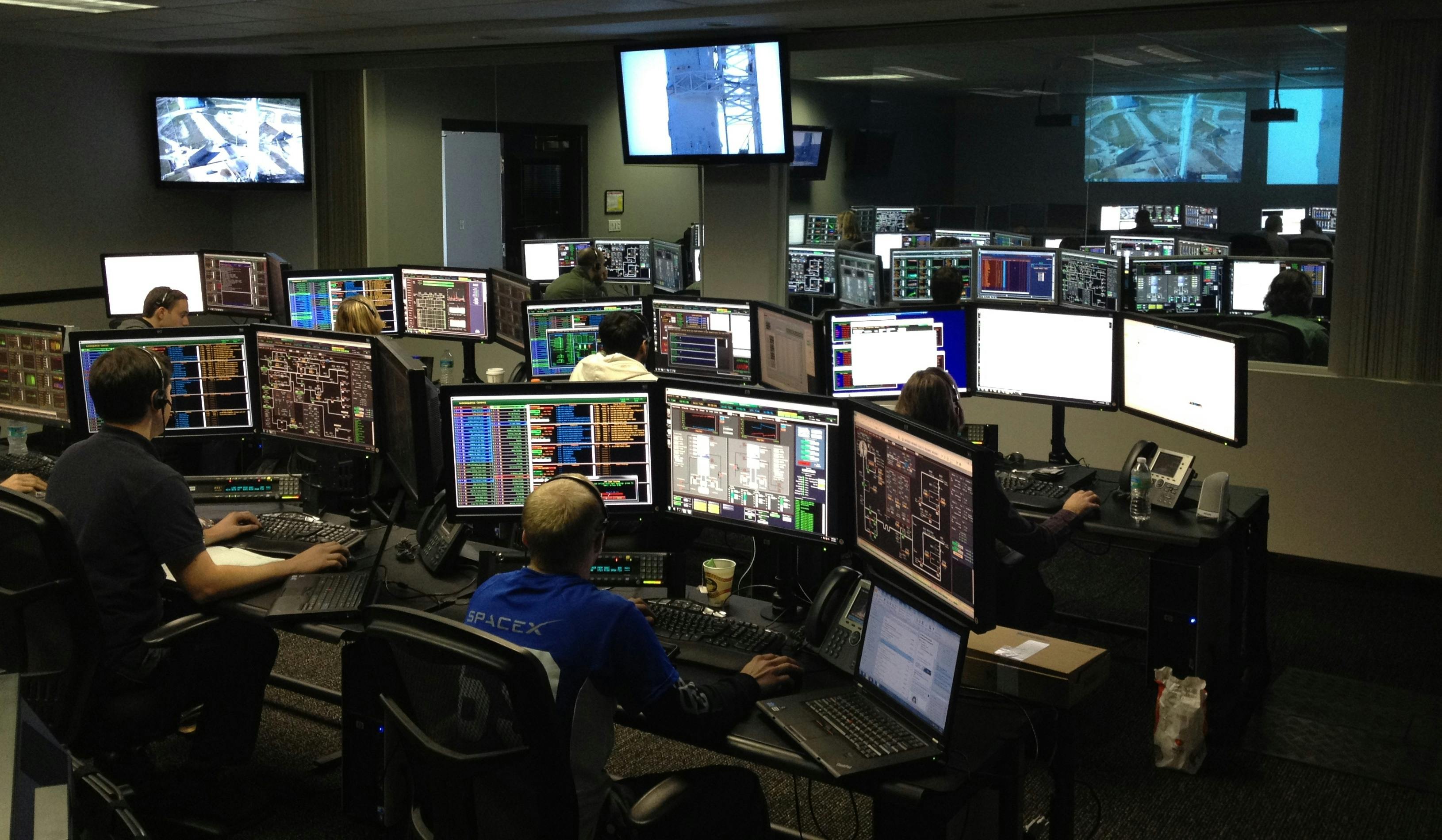 Descrição: Dashboard em tempo real mostrando comparação entre NOC tradicional (equipe de 23 técnicos reagindo a 847 alertas vermelhos) vs. NOC com AIOps (8 supervisores com IA processando 3,2 TB/segundo), destacando diferença de custos: R$ 4,7 milhões vs. R$ 1,8 milhão anual.
