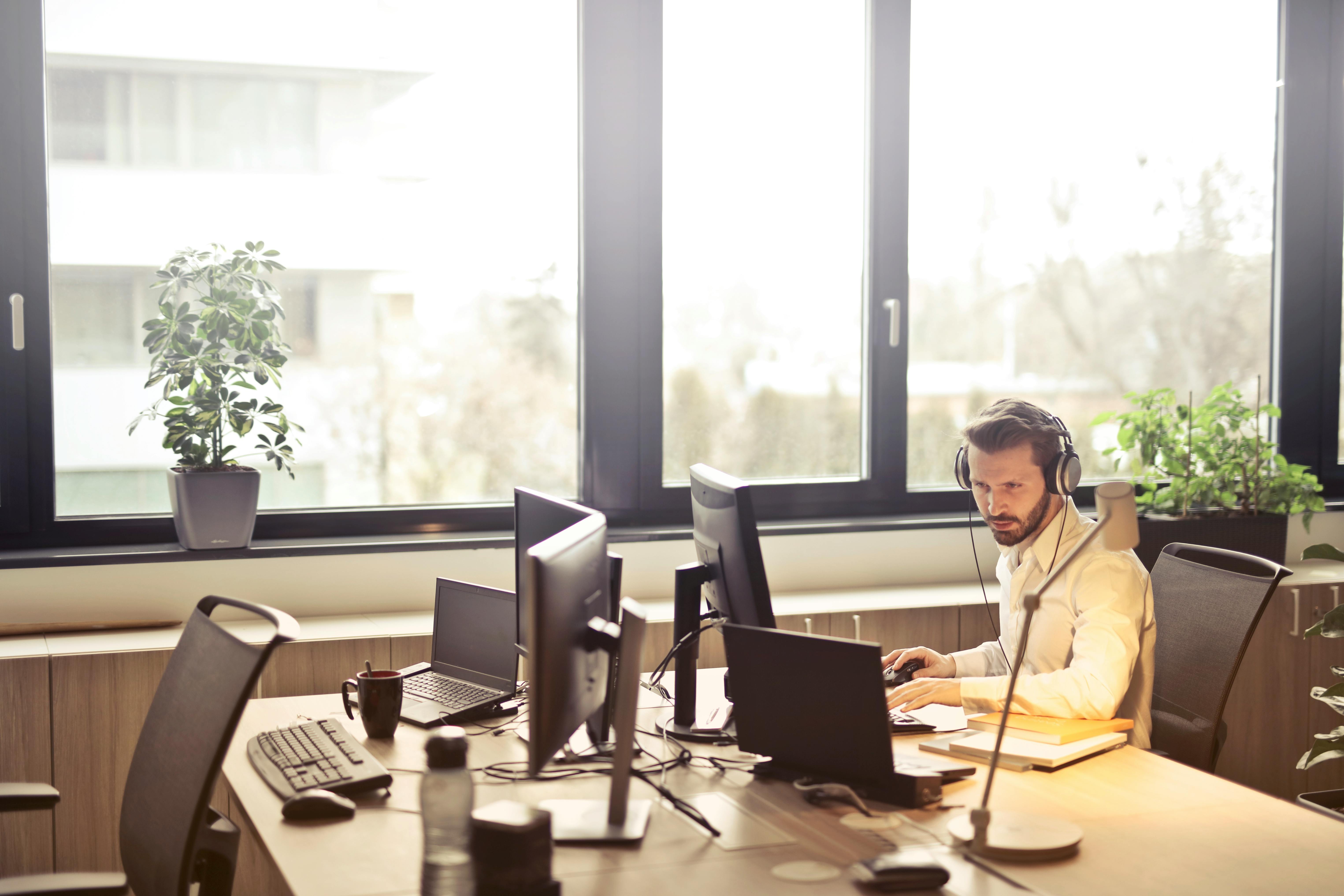 Call center tradicional com fileiras de mesas vazias e headsets abandonados, simbolizando o "Service Desk Apocalipse", contrastando com uma única workstation moderna onde um especialista em IA monitora dashboards automatizados que mostram "73% de tickets resolvidos automaticamente".