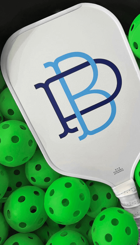 Palm Beach branded pickleball paddle surrounded by bright green pickleballs.