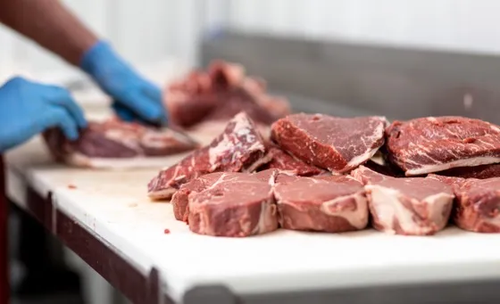 Worker butchering steaks on table