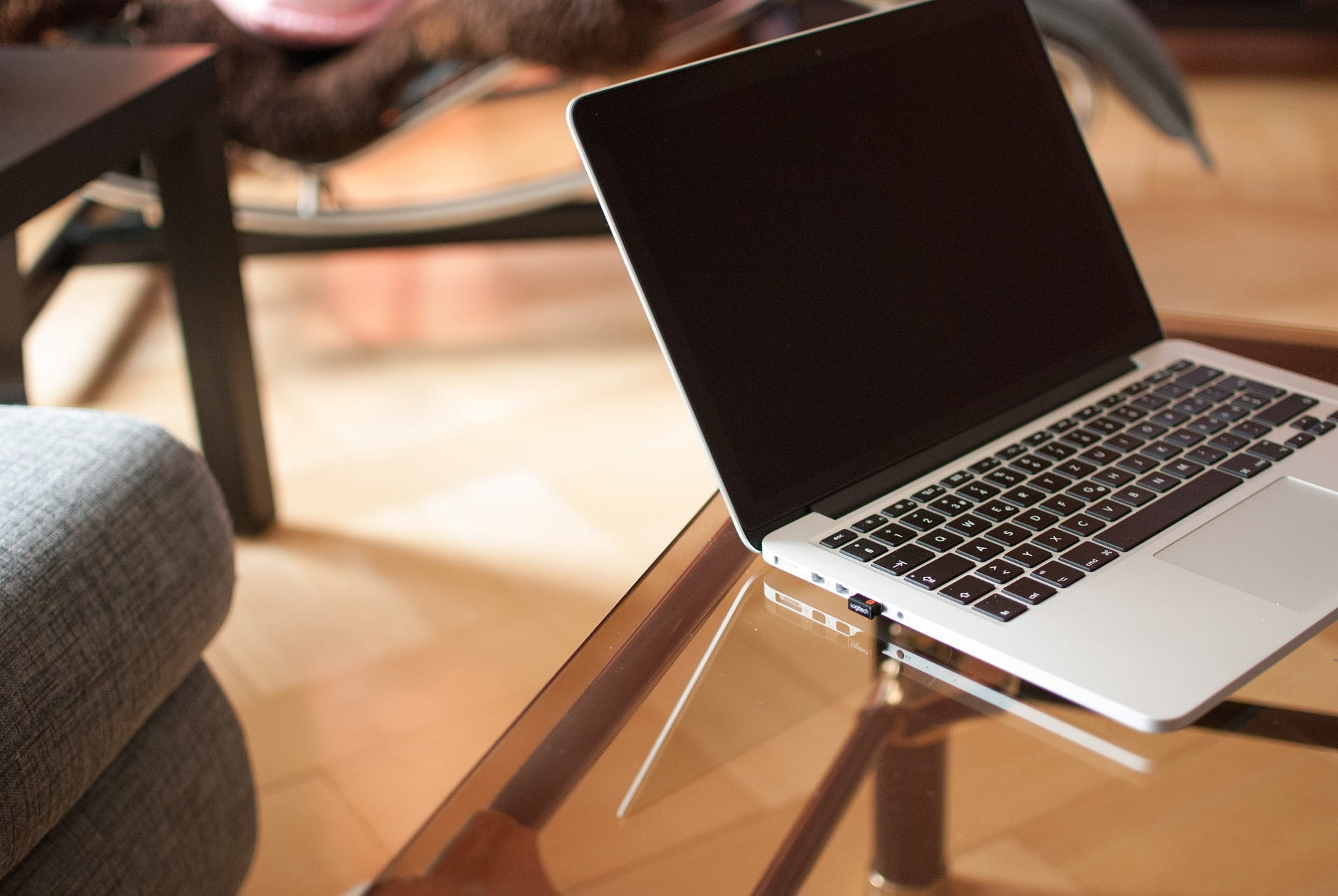 A laptop on a glass coffee table.