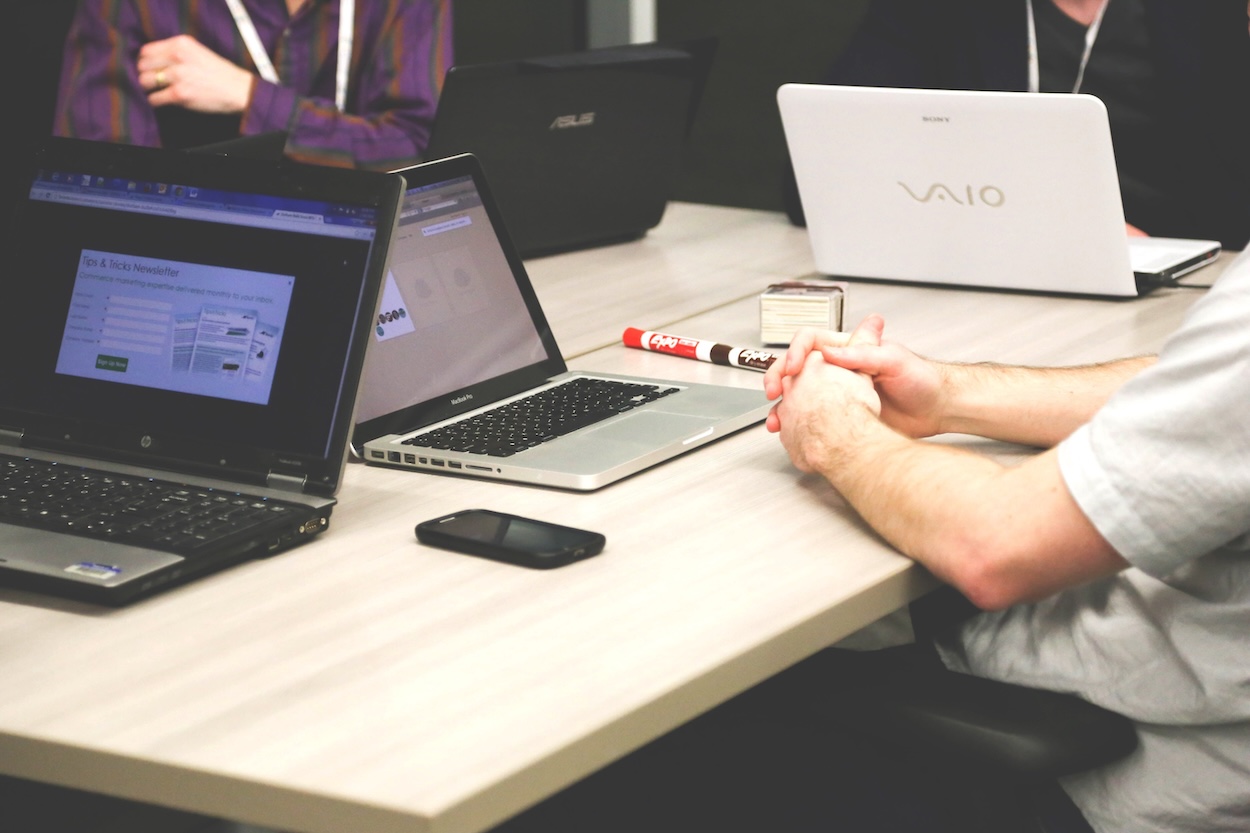 People sat around a table with laptop out and open on the table.