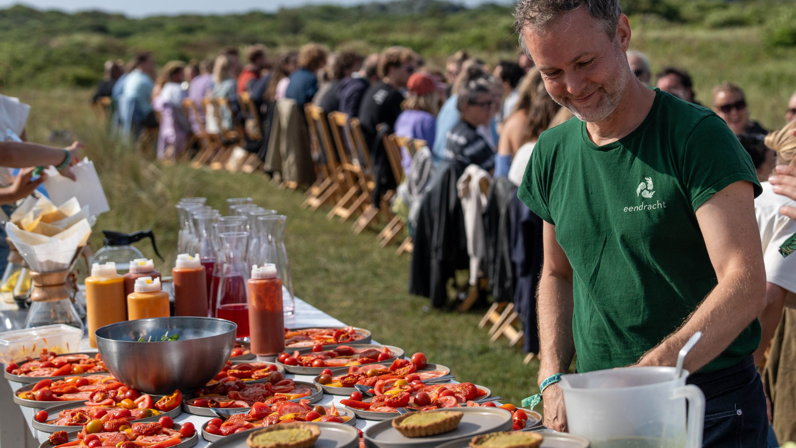 Afbeelding van Chef Pepijn die in de natuur bordjes aan het klaarmaken is met tomaten erop