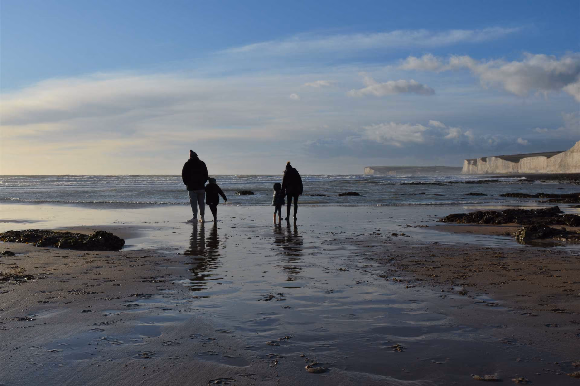 A family walking on a beach at sundown