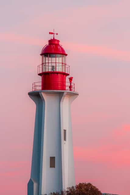 Lighthouse with a red top during a purple sunset