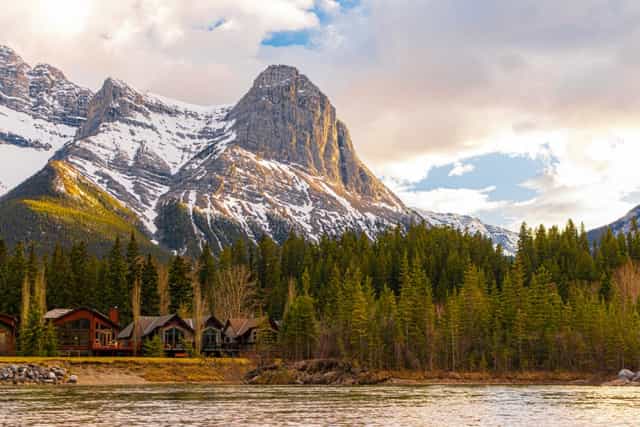 Wooden cabins in forest below mountain peak