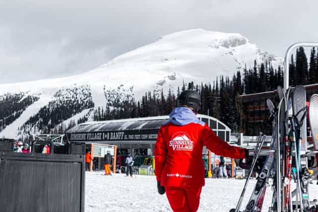 Mountain ranger wearing red winter outfit looking at distant mountain