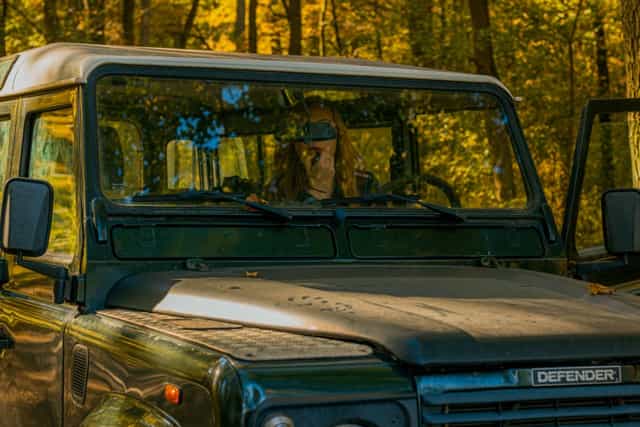 Woman driver putting on lipstick in an offroad car