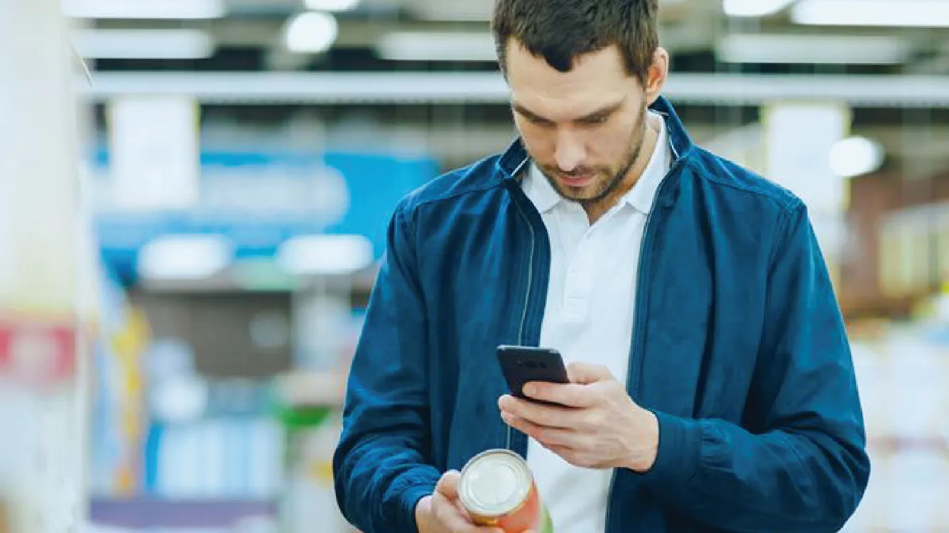 A man in a store is scanning a can with his smartphone.