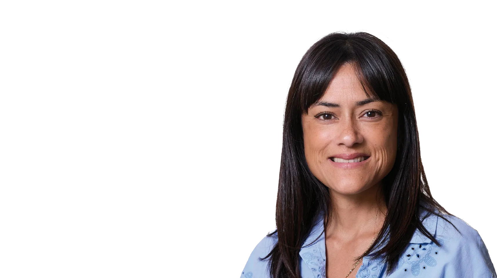 Smilende kvinde med mørkt hår iført lyseblå skjorte på transparent baggrund.