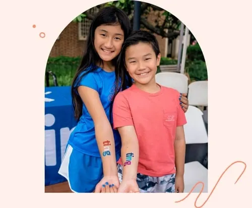 Children smiling, showing Ting stickers on their arms at a community event.