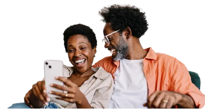 A man and woman smile at each other while looking at their cell phone, sharing a joyful moment together.