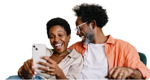 A man and woman smile at each other while looking at their cell phone, sharing a joyful moment together.